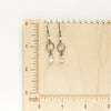 The moonstone and pearl hoop earrings on a wooden ruler for size reference