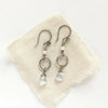 The moonstone and pearl hoop earrings styled on tan linen