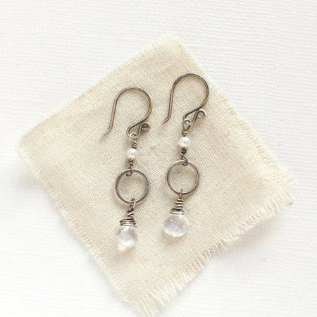 The moonstone and pearl hoop earrings styled on tan linen