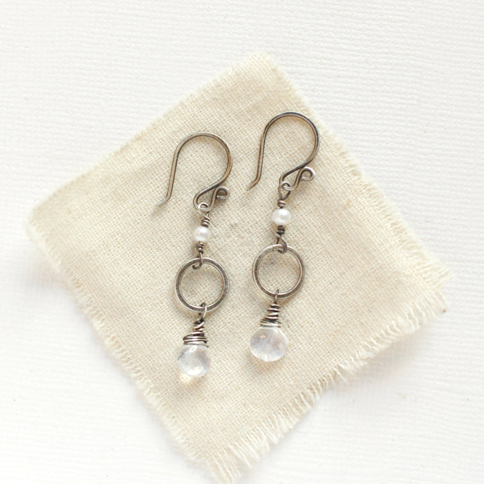 The moonstone and pearl hoop earrings styled on tan linen