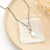 The moonstone and pearl necklace styled on a tan plate with linen and dried grass