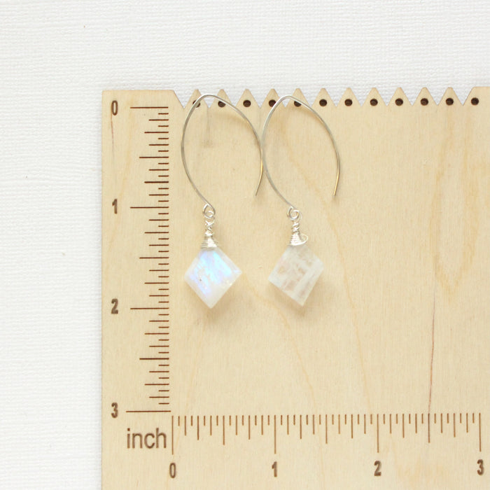 The moonstone slice earrings on a wooden ruler for size reference