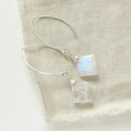 The moonstone slice petal earrings styled on tan linen