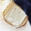 The moonstone swing earrings styled on wood with blue velvet and dried grass