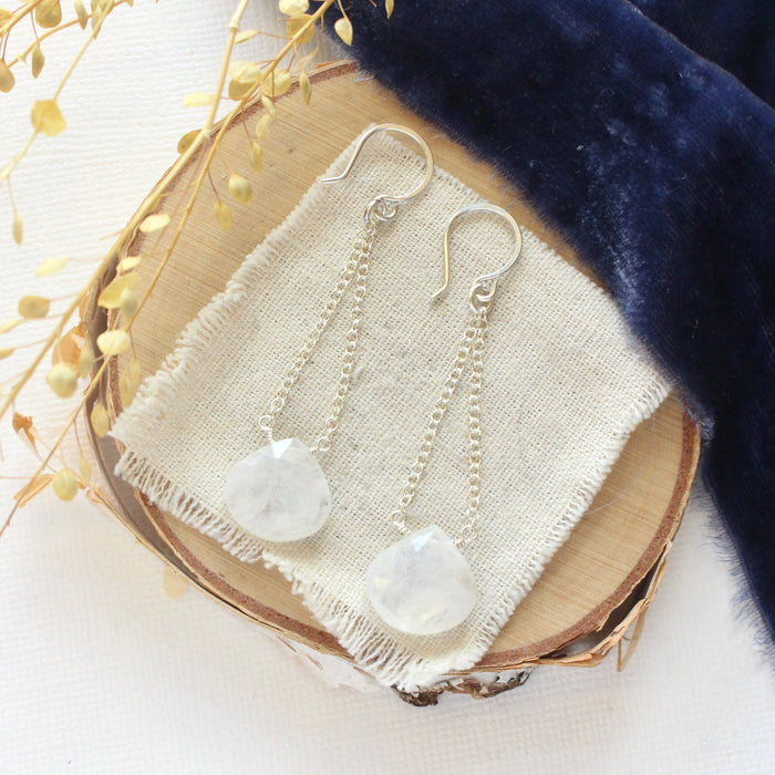 The moonstone swing earrings styled on wood with blue velvet and dried grass