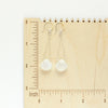 The moonstone swing earrings on a wooden ruler for size reference