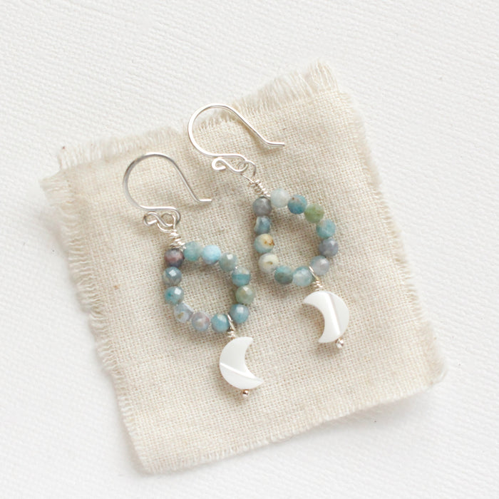 The mother of pearl and aquamarine hoop earrings styled on tan linen