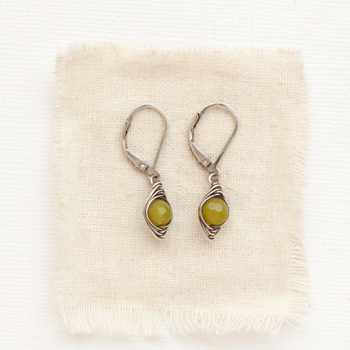 The silver wrapped olivine jade earrings styled on tan linen
