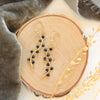 The onyx wrapped gold vine earrings styled on wood with gray velvet and dried grass