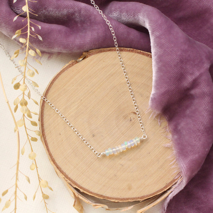 The opal bar necklace styled on wood with purple velvet and dried grass