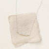 The opal bar necklace styled on tan linen