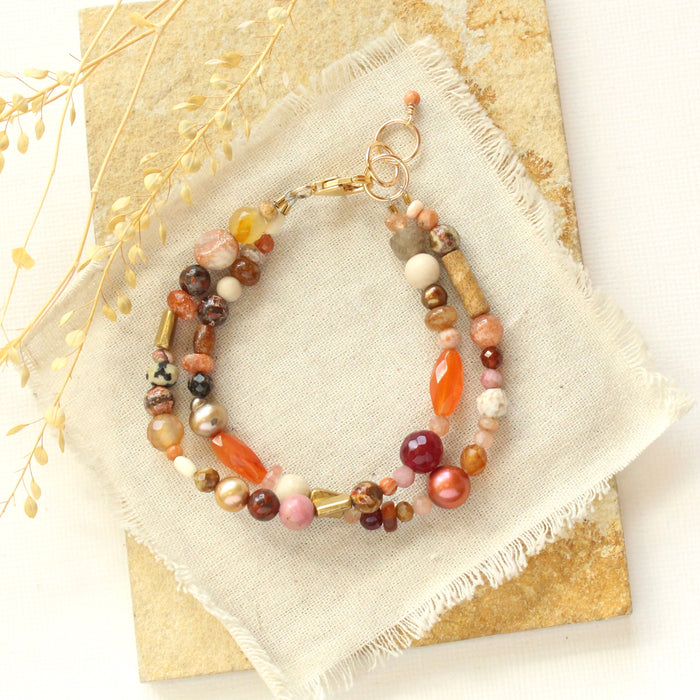The orange crush bracelet styled on a tan rock with linen and dried grass