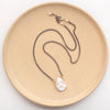 The organic pearl mixed metal necklace styled on a tan plate to show the adjustable lobster clasp closure