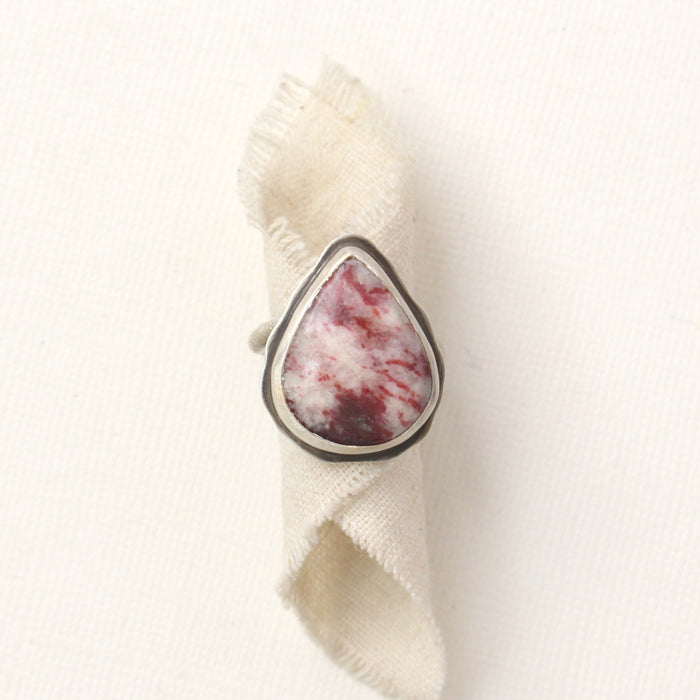 The organic thulite and little ruby ring styled on rolled tan linen
