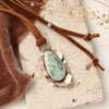 The organic variscite leather necklace styled on a tan rock with orange velvet and dried grass