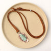 The organic variscite leather necklace styled on a tan plate to show the entire necklace