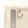 A pakal hoop post earring next to a ruler for size reference