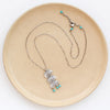 The pakal trio turquoise necklace styled on a tan plate to show the adjustable lobster clasp closure