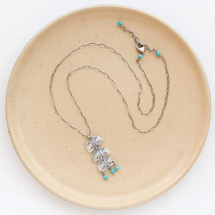 The pakal trio turquoise necklace styled on a tan plate to show the adjustable lobster clasp closure