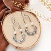 The pearl columbine hoop earrings styled on wood with orange velvet and dried grass