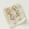The pearl and moonstone fringe earrings styled on tan linen