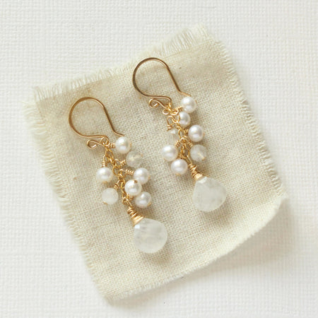 The pearl and moonstone fringe earrings styled on tan linen