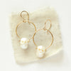 The carved pearl skull hoop earrings styled on tan linen