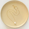 The carved pearl skull necklace styled on a tan plate to show the adjustable lobster clasp closure