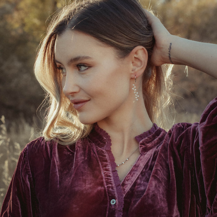 The pearl wrapped oxidized silver vine earrings being worn by a model