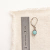 A wrapped amazonite earring next to a ruler for size reference