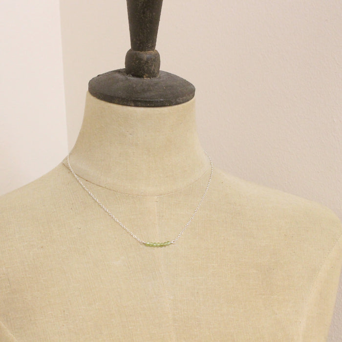 A mannequin wearing the peridot bar necklace