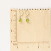 The peridot drop earrings on a wooden ruler for size reference