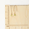 The peridot drop hook earrings on a wooden ruler for size reference
