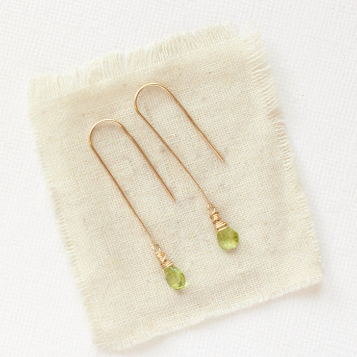 The peridot drop hook earrings styled on tan linen