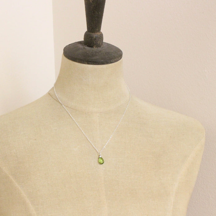A mannequin wearing the peridot drop necklace