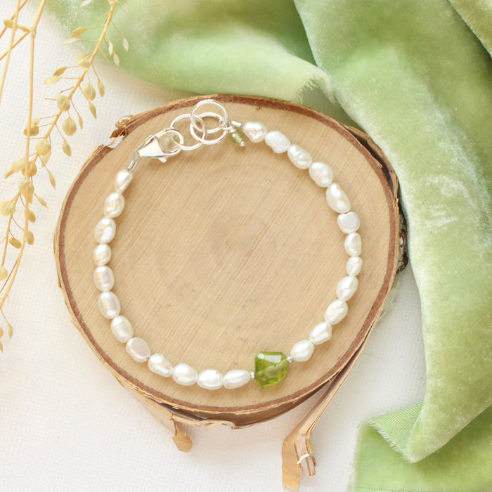 The pearl and peridot bracelet styled on wood with green velvet and dried grass