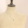 A mannequin wearing the peridot and pearl charm necklace