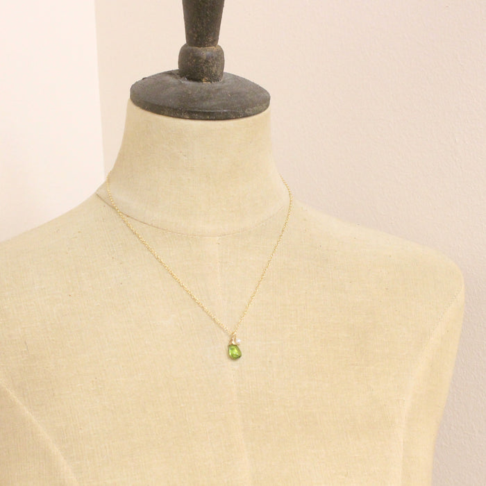 A mannequin wearing the peridot and pearl charm necklace