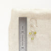 A peridot trio hoop earring next to a ruler for size reference