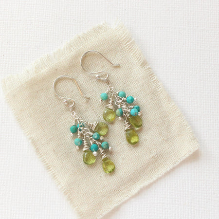 The turquoise & peridot fringe earrings styled on tan linen