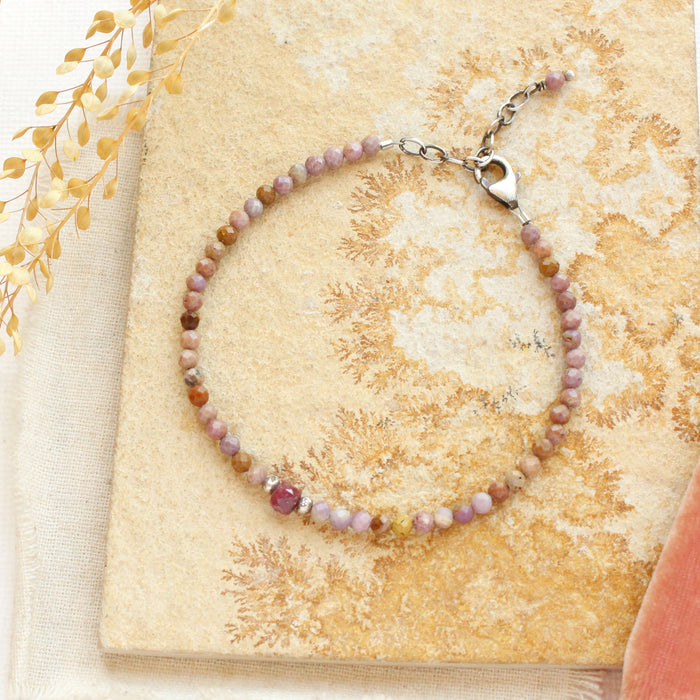 The phosphosiderite and ruby bracelet styled on a tan rock with linen and dried grass