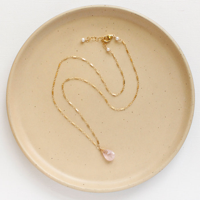 The morganite drop necklace styled on a tan plate to show the adjustable lobster clasp closure