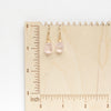 The morganite drop earrings styled on a wooden ruler for size reference