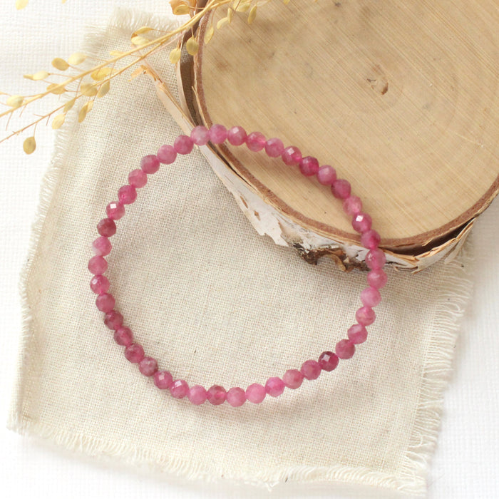 The pink tourmaline stretch bracelet styled on wood with linen and dried grass