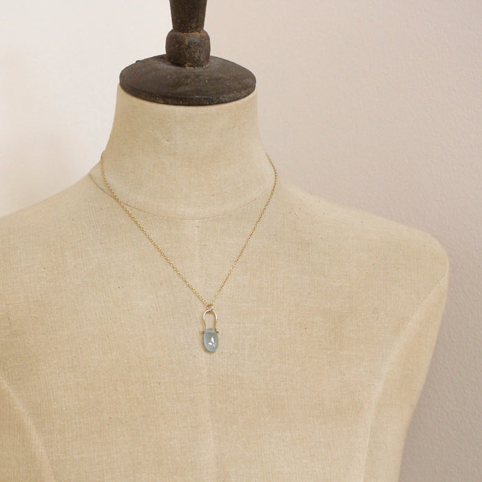 A mannequin wearing the pinned aquamarine gold necklace