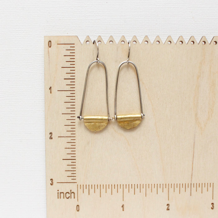 The pinned mythos earrings on a wooden ruler for size reference
