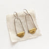 The pinned mythos earrings styled on tan linen