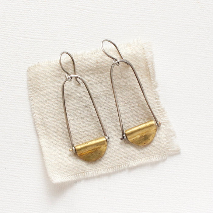 The pinned mythos earrings styled on tan linen