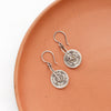 The pinned columbine disc earrings styled on an orange plate