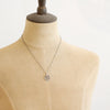 A mannequin wearing the pinned columbine disc necklace